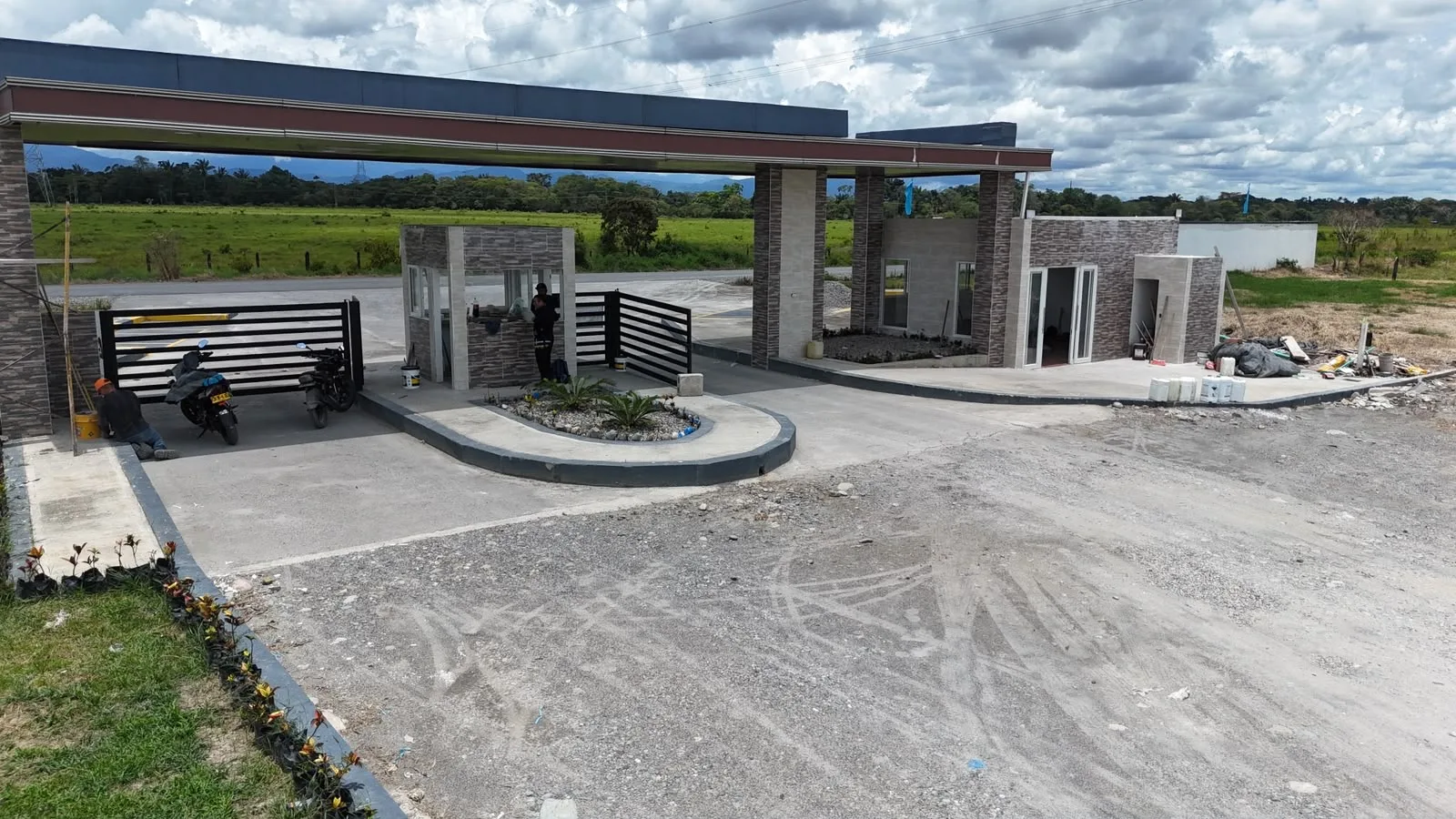 Portería con caseta de vigilancia y jardín de acceso