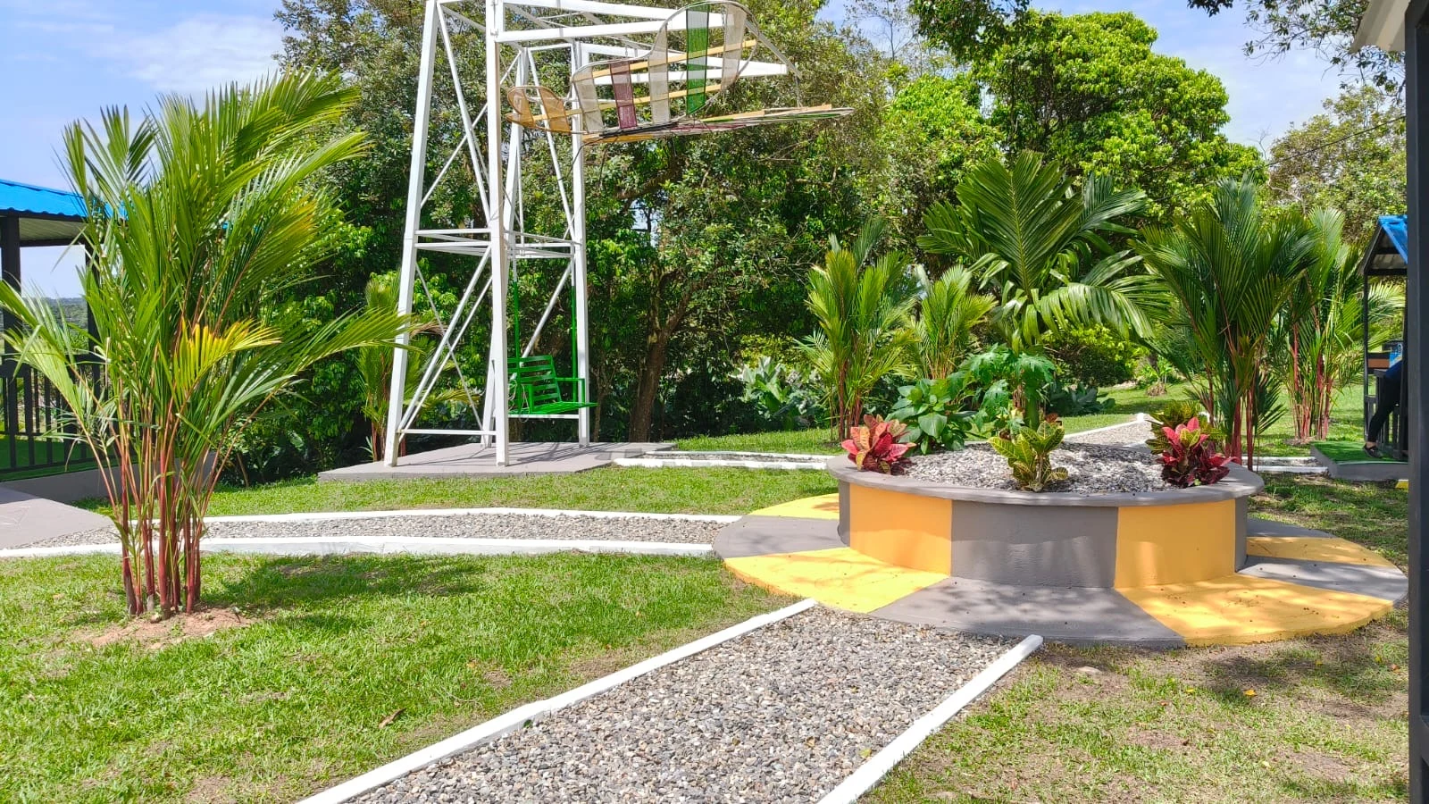 Columpio en estructura blanca y jardinera circular amarilla con plantas