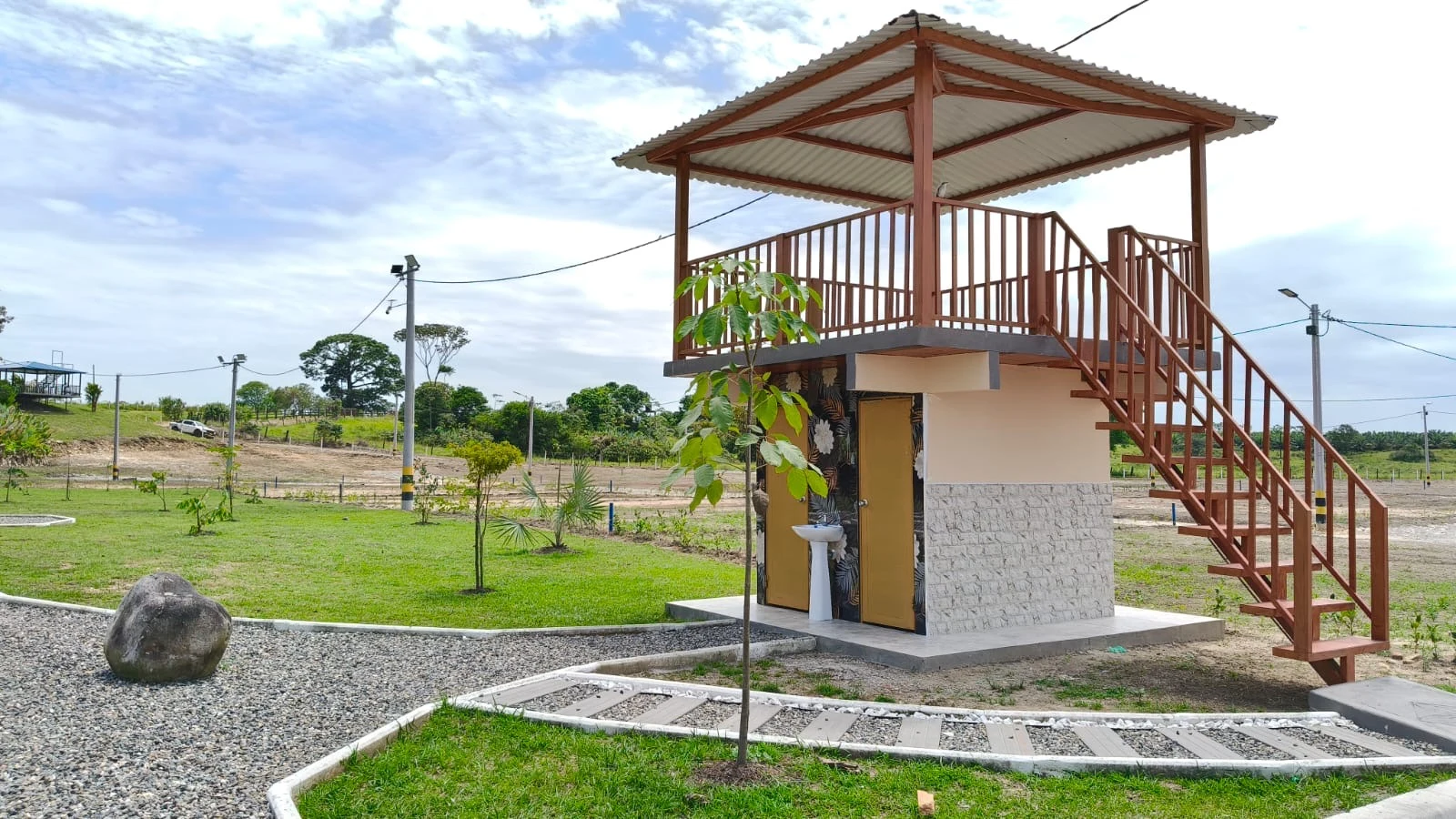 Mirador de madera de dos niveles con escalera, junto a zonas verdes