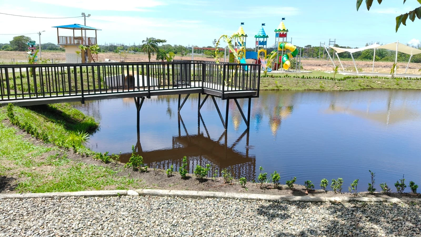 Lago de Verdecielo con muelle de baranda negra y parque infantil al fondo