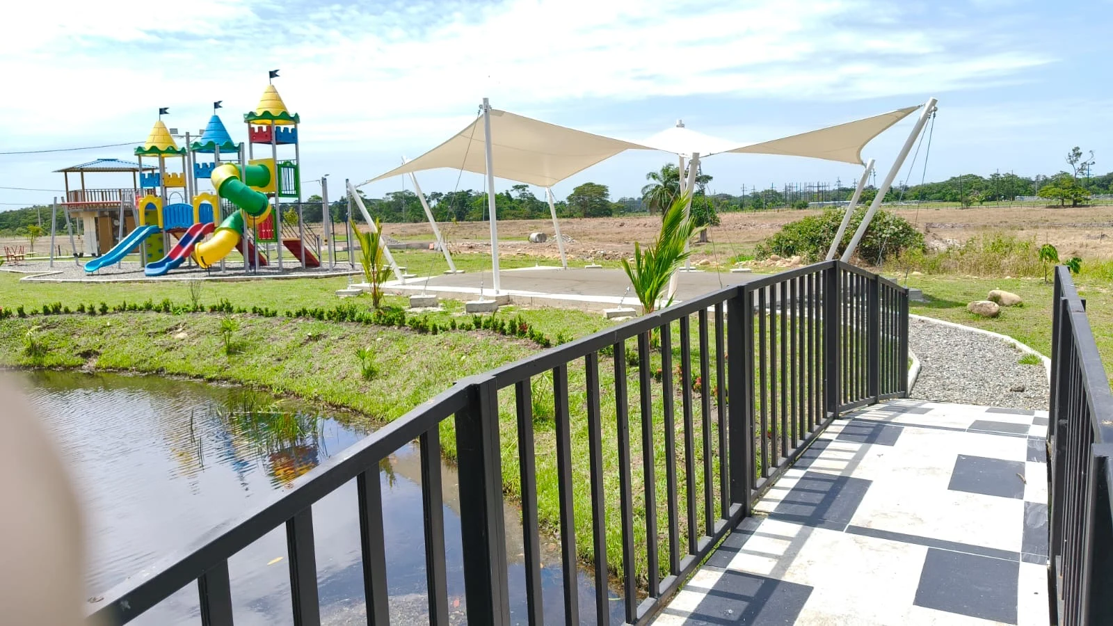 Puente sobre el lago con vista al parque infantil y la zona con toldos