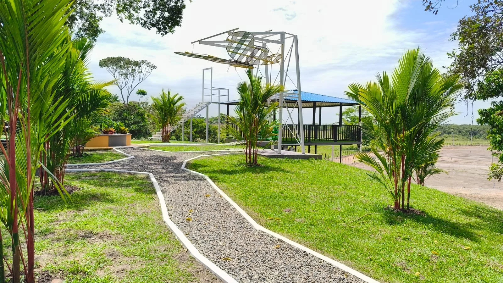Sendero en gravilla entre palmas hacia el mirador y el kiosco